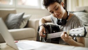 Smiling girl playing a guitar at home